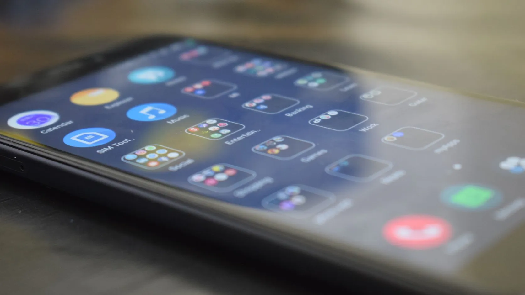 Gros plan en biais sur l'écran d'un smartphone affichant des dossiers d'applications et une icône SIM Toolkit
