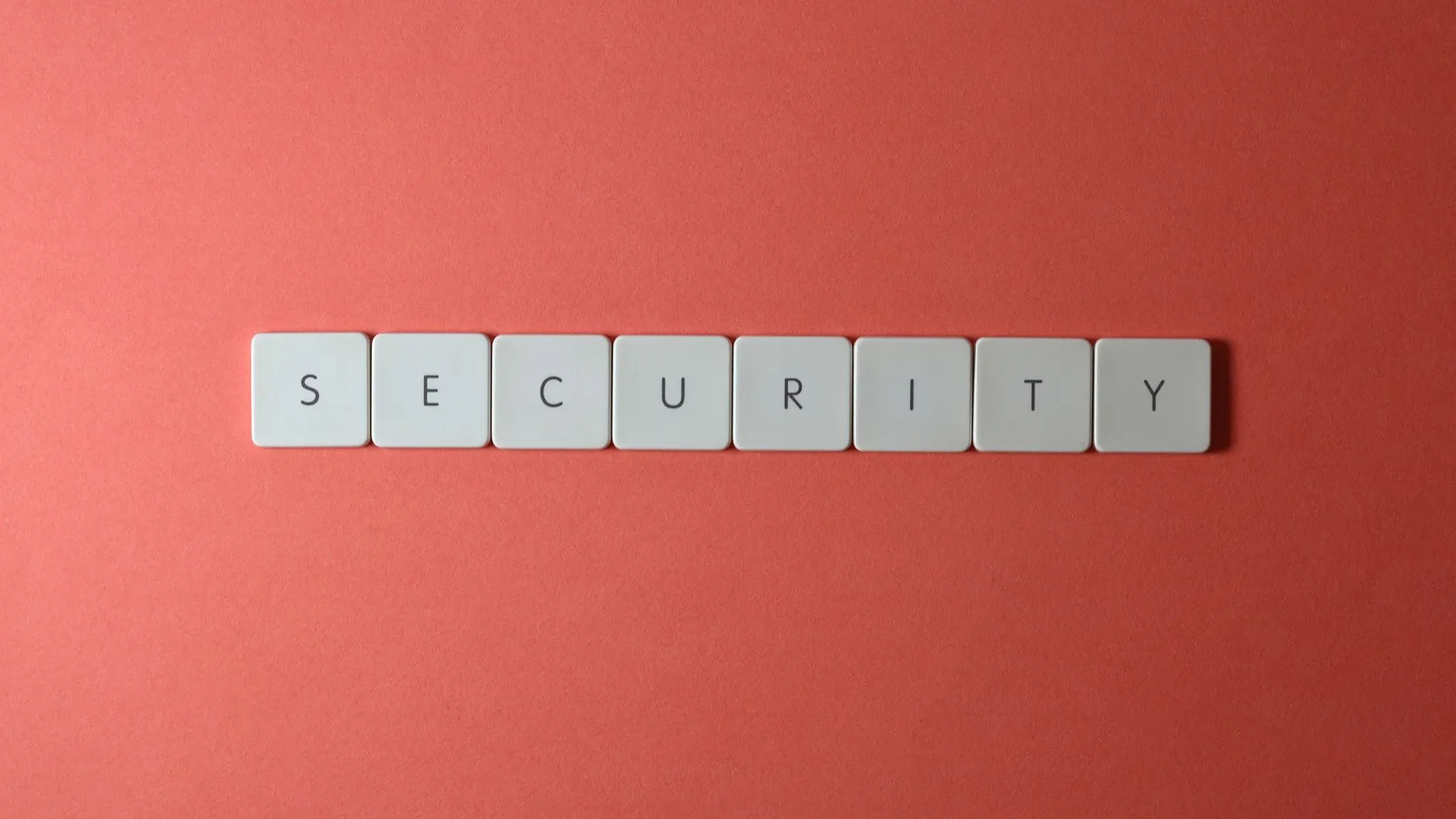 Touches de clavier blanches formant le mot security sur un fond rouge corail