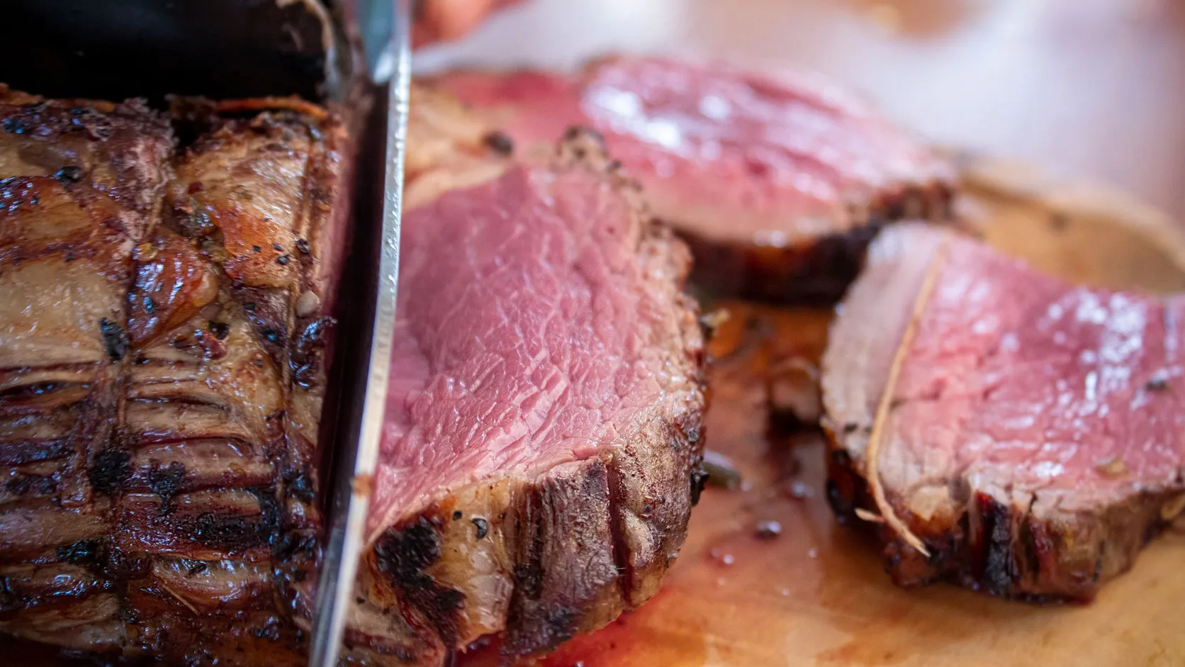 Rôti de bœuf rosé à cœur tranché au couteau sur une planche en bois