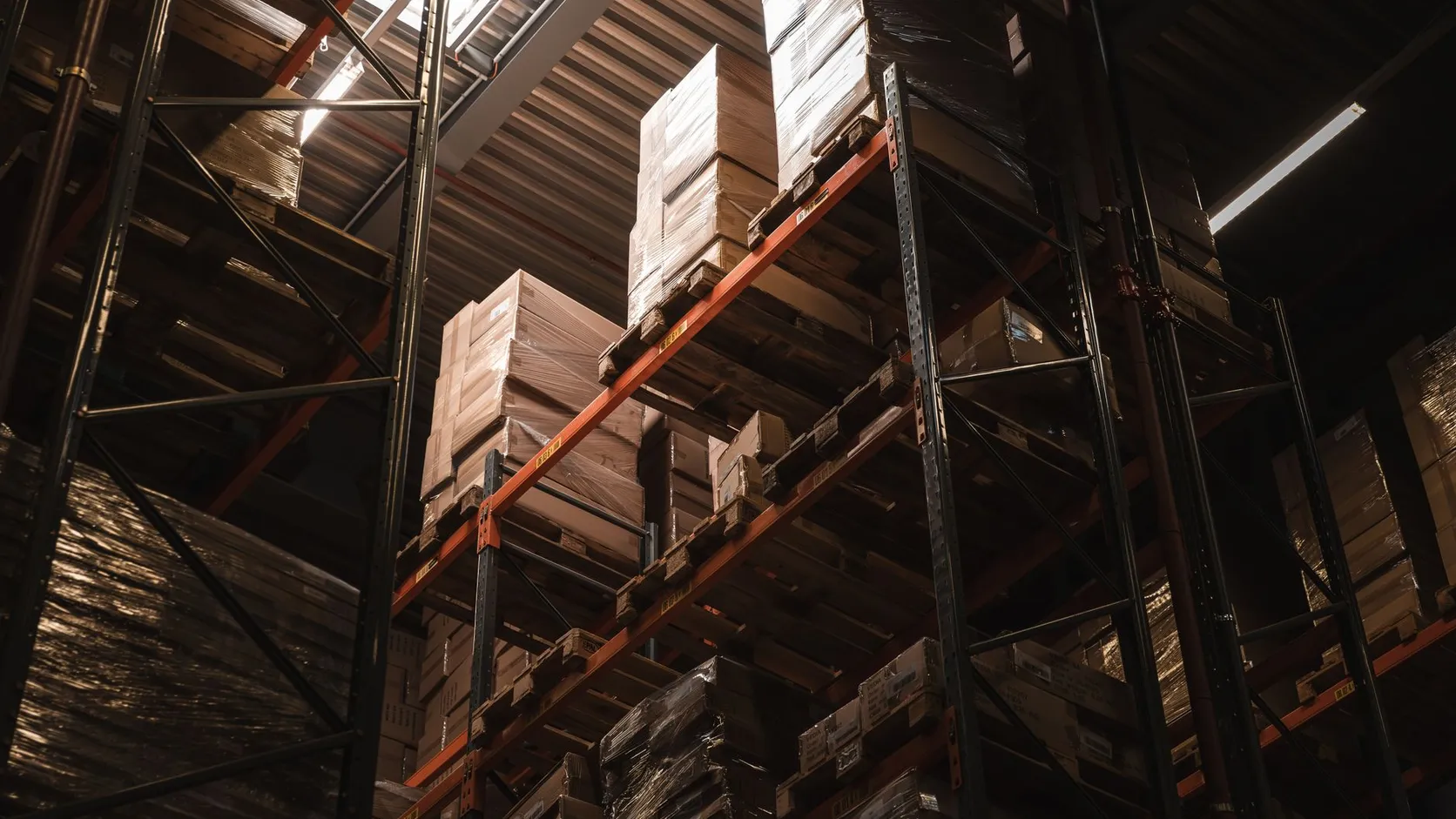 Cartons filmés sur des palettes, rangés sur les hauts rayonnages métalliques d'un entrepôt