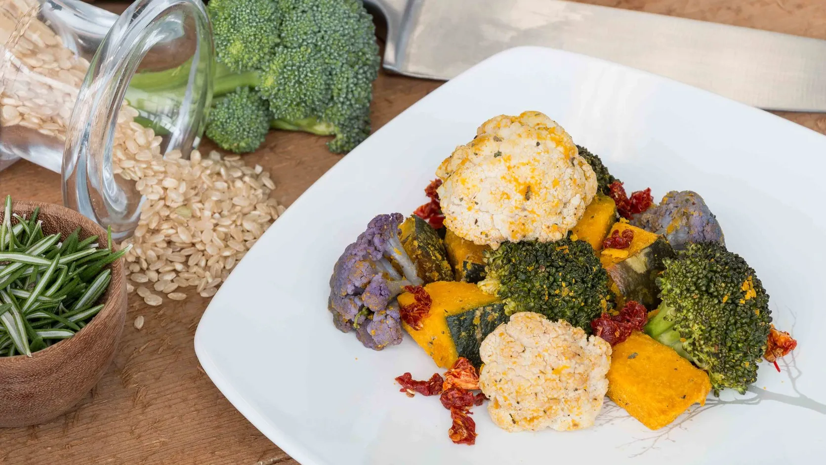Assiette de brocoli, chou-fleur blanc et violet, potimarron et tomates séchées, à côté d'un bocal de riz renversé