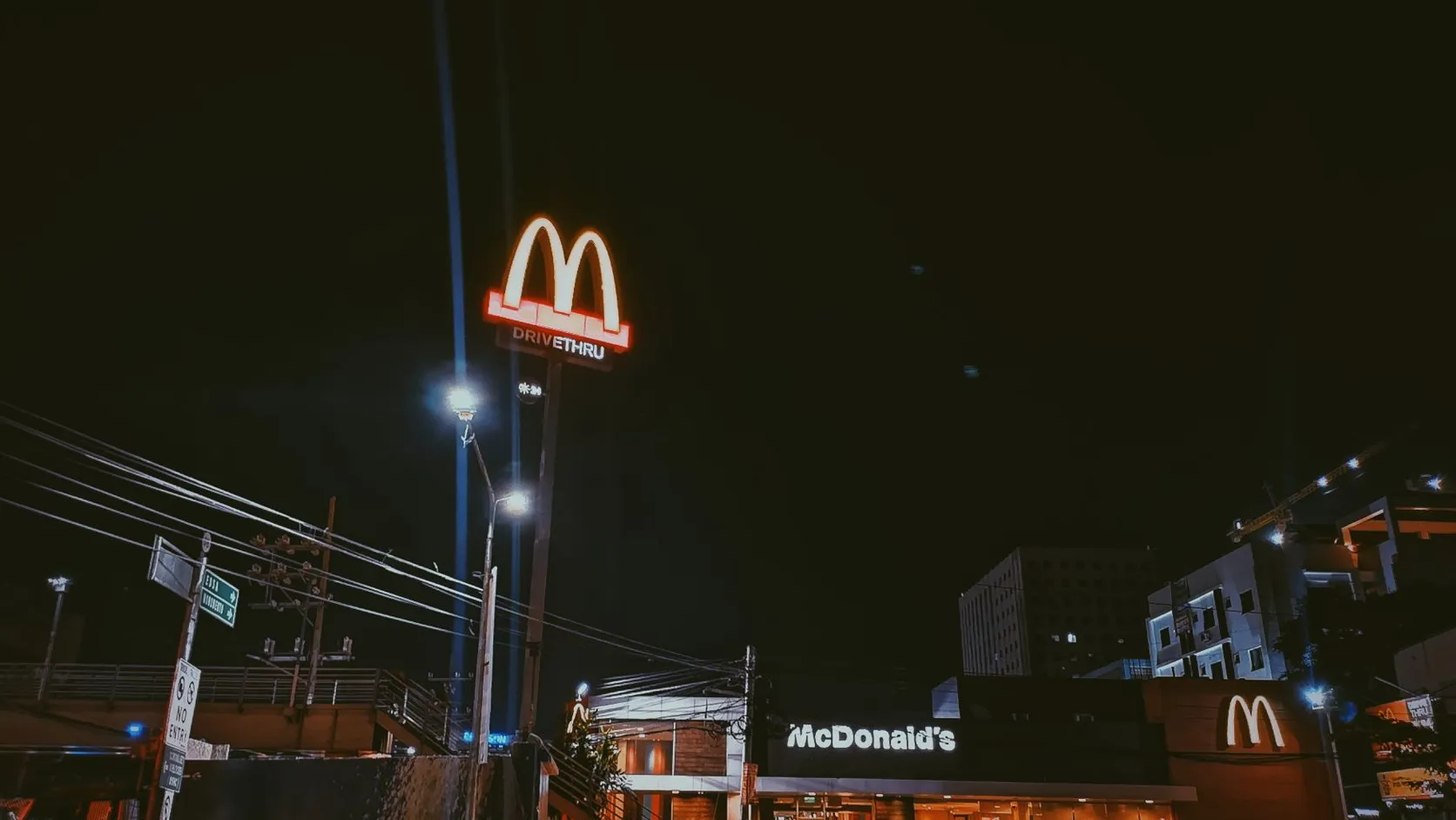 Restaurant McDonald's de nuit avec son enseigne lumineuse Drive Thru et la façade éclairée au bord d'une rue