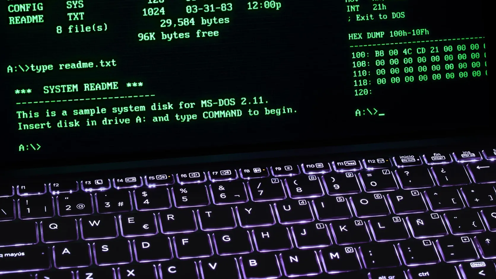 Écran de terminal vert sur fond noir au-dessus d'un clavier d'ordinateur portable rétroéclairé